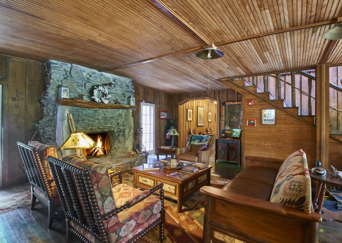 Rustic living room with wooden walls, a stone fireplace, and cozy seating.