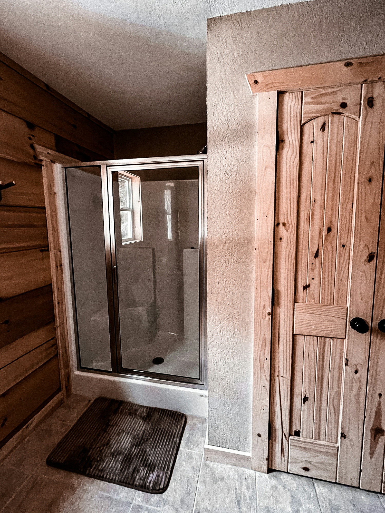 Bathroom with a glass shower enclosure and wooden door.