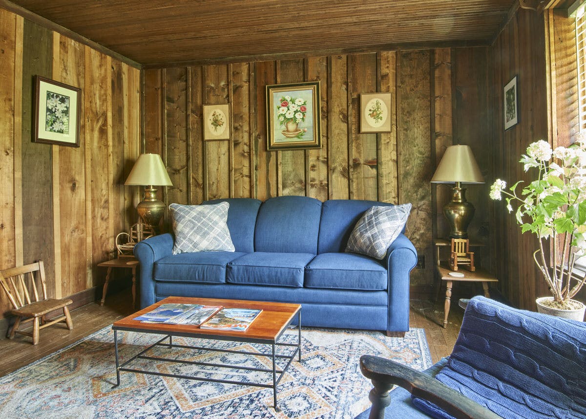 Cozy living room with a blue sofa, wooden walls, and framed artwork.