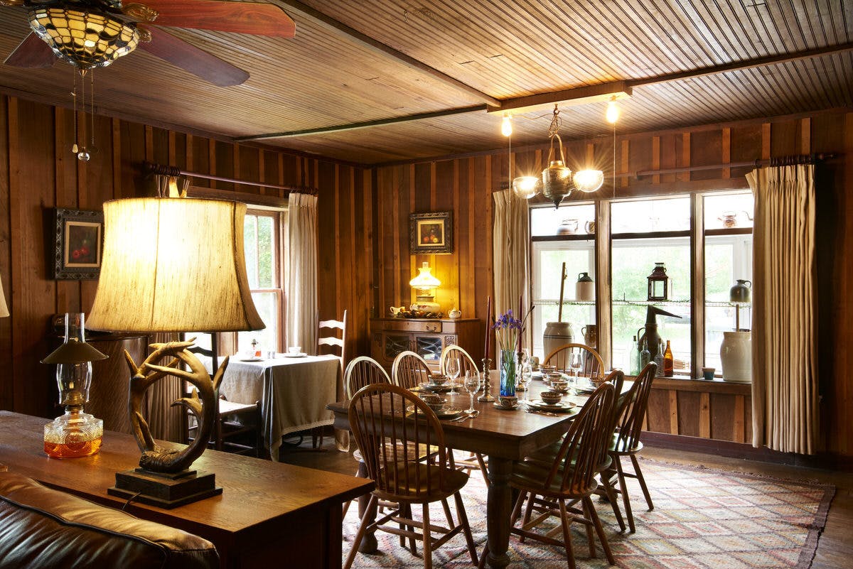 Rustic dining room with a large wooden table, chairs, and warm lighting.