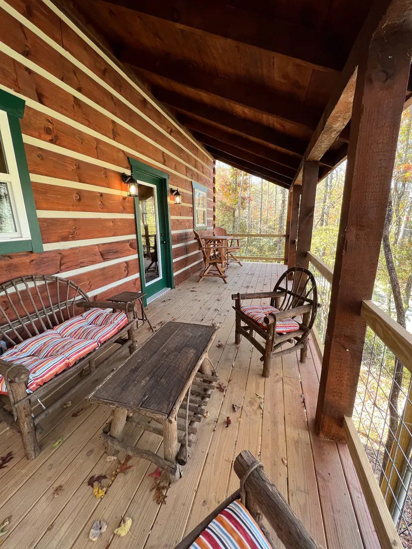 Covered wooden porch with rustic furniture and colorful cushions.